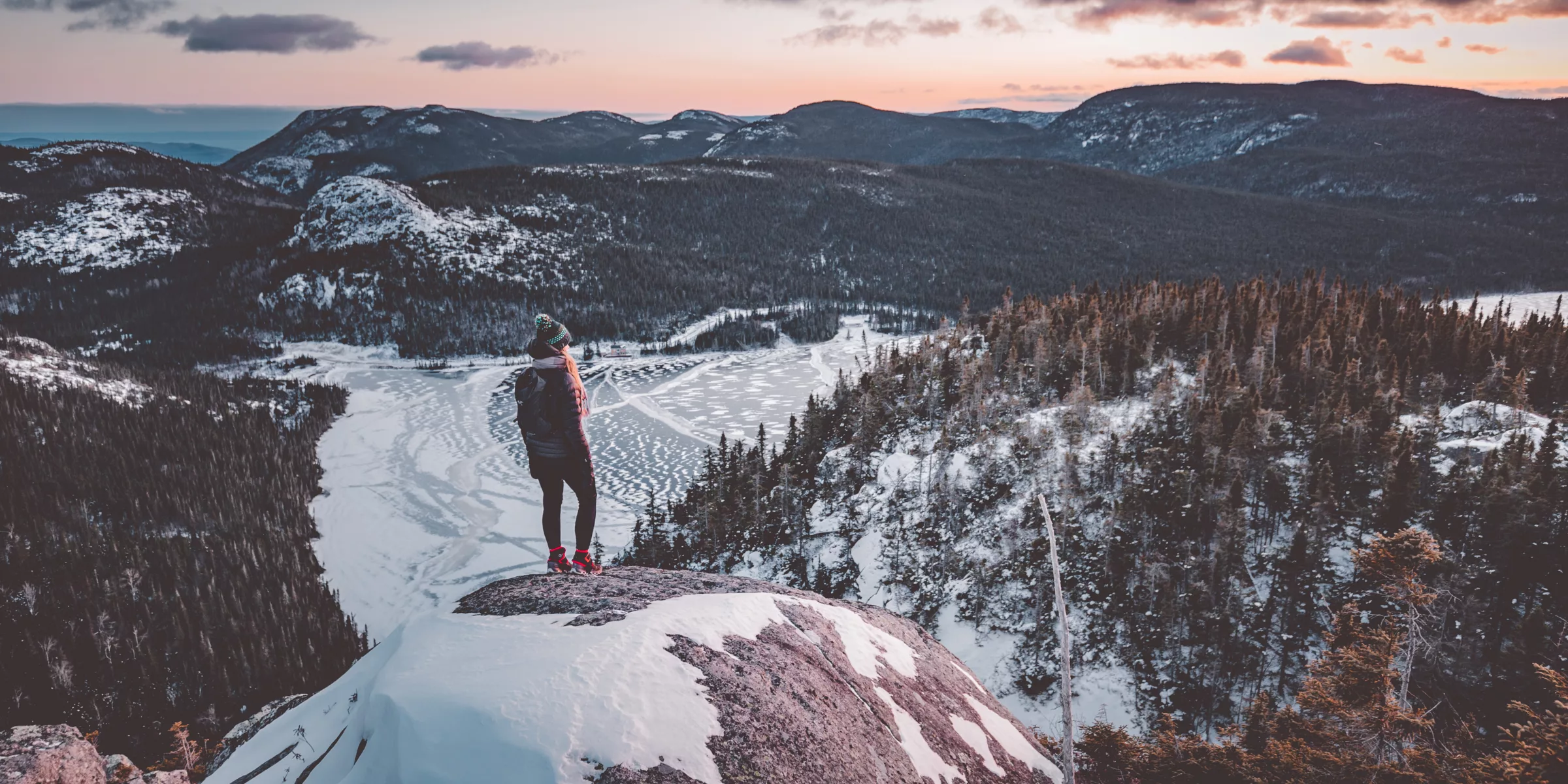 femme au sommet d'une colline avec une vue surplombant la vallé au coucher dusoleil