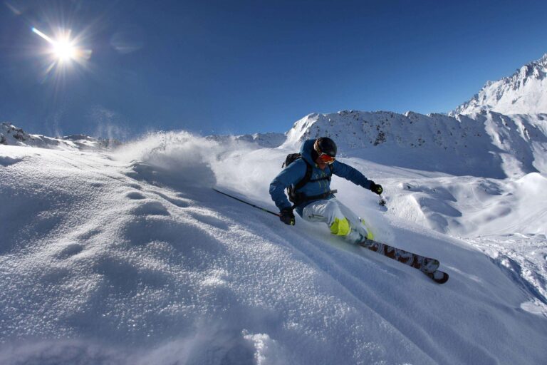 Skieur qui descend une montagne de neige en pleine journée ensoleillé